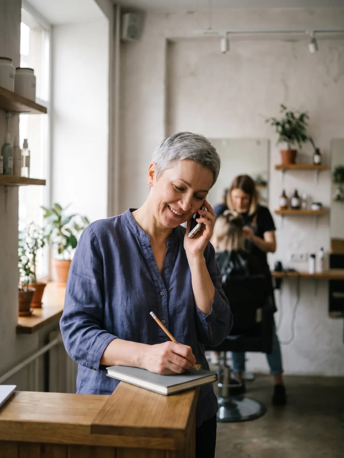 Владелица салона обсуждает план по телефону и делает пометку